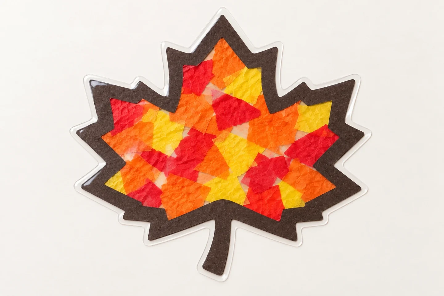 The finished tissue-paper leaf has a continuous brown border and a narrow clear sealed margin around every edge.