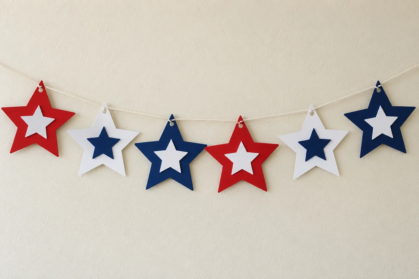 Six flat layered paper stars threaded onto cotton string