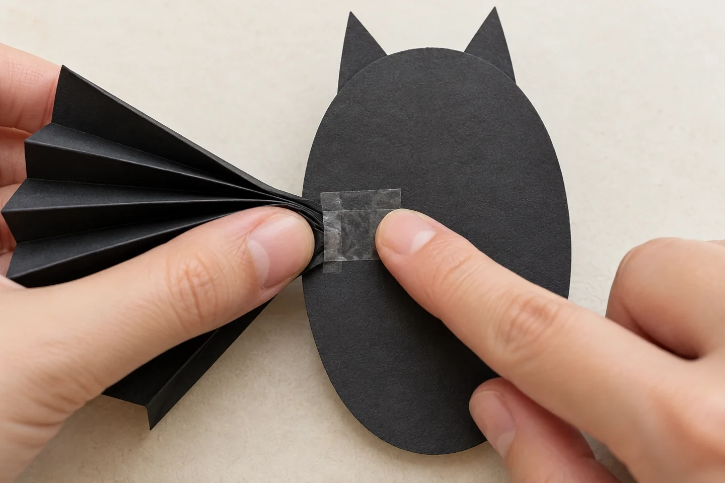 Clear tape secures a pinched accordion wing behind the bat’s body.
